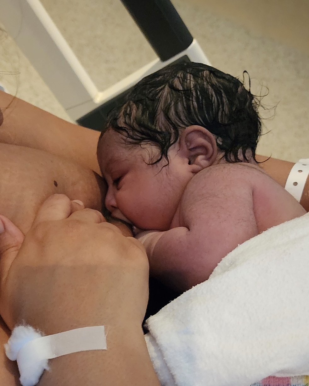 A newborn baby breastfeeding in their mother’s arms